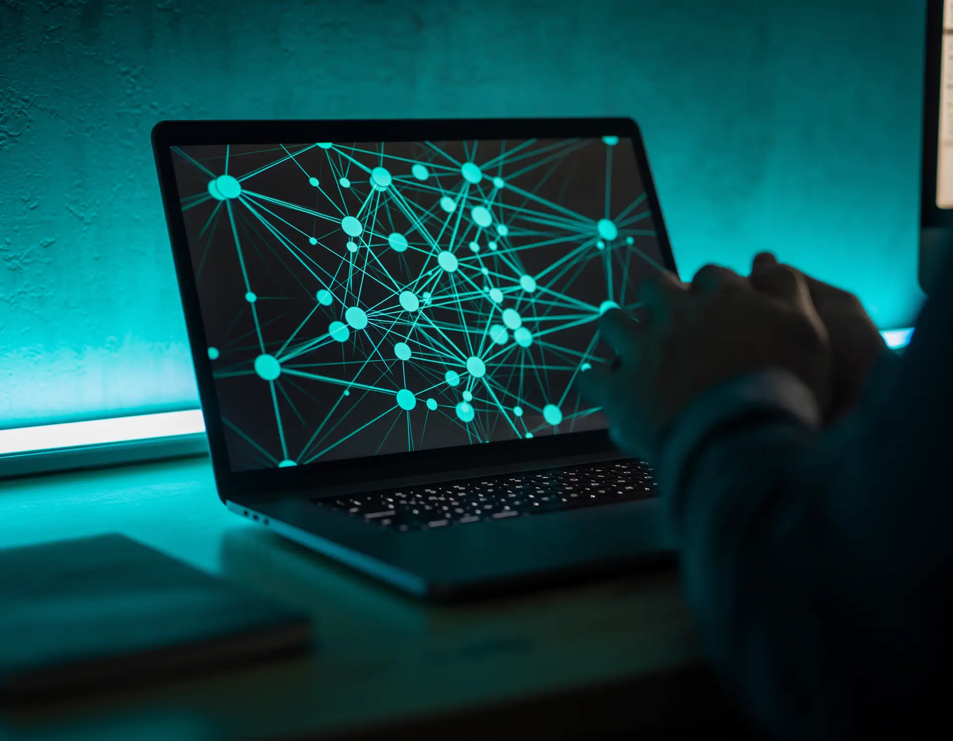 Person arbeitet an einem Laptop mit visualisiertem digitalen Netzwerk aus Knotenpunkten und Linien auf dem Bildschirm