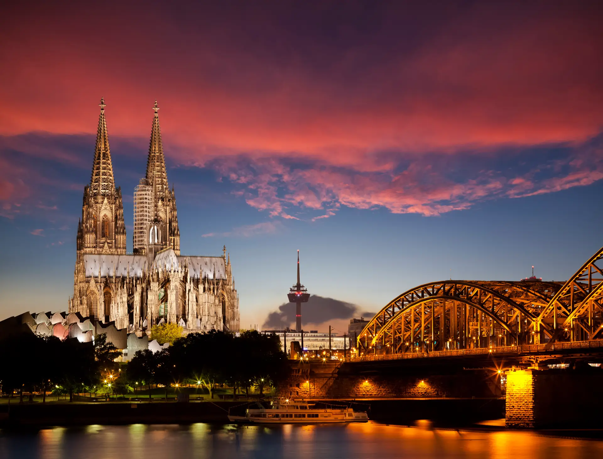 Kölner Dom und Hohenzollernbrücke bei Sonnenuntergang mit rotem Himmel über dem Rhein