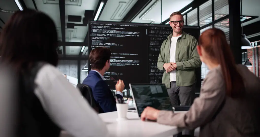 IT-Team bei Präsentation mit Code auf großem Bildschirm im modernen Konferenzraum