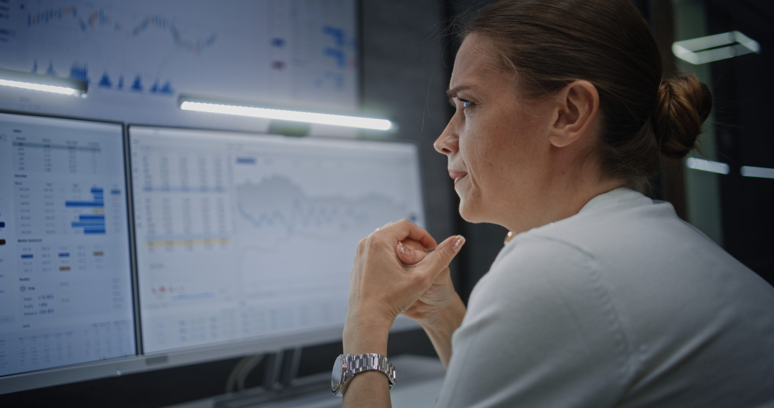 Finanzanalystin analysiert Daten und Marktberichte an mehreren Bildschirmen – Earnings Call Vorbereitung mit KI