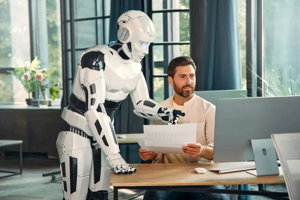Humanoid robot supports man with analysis at the computer in the office