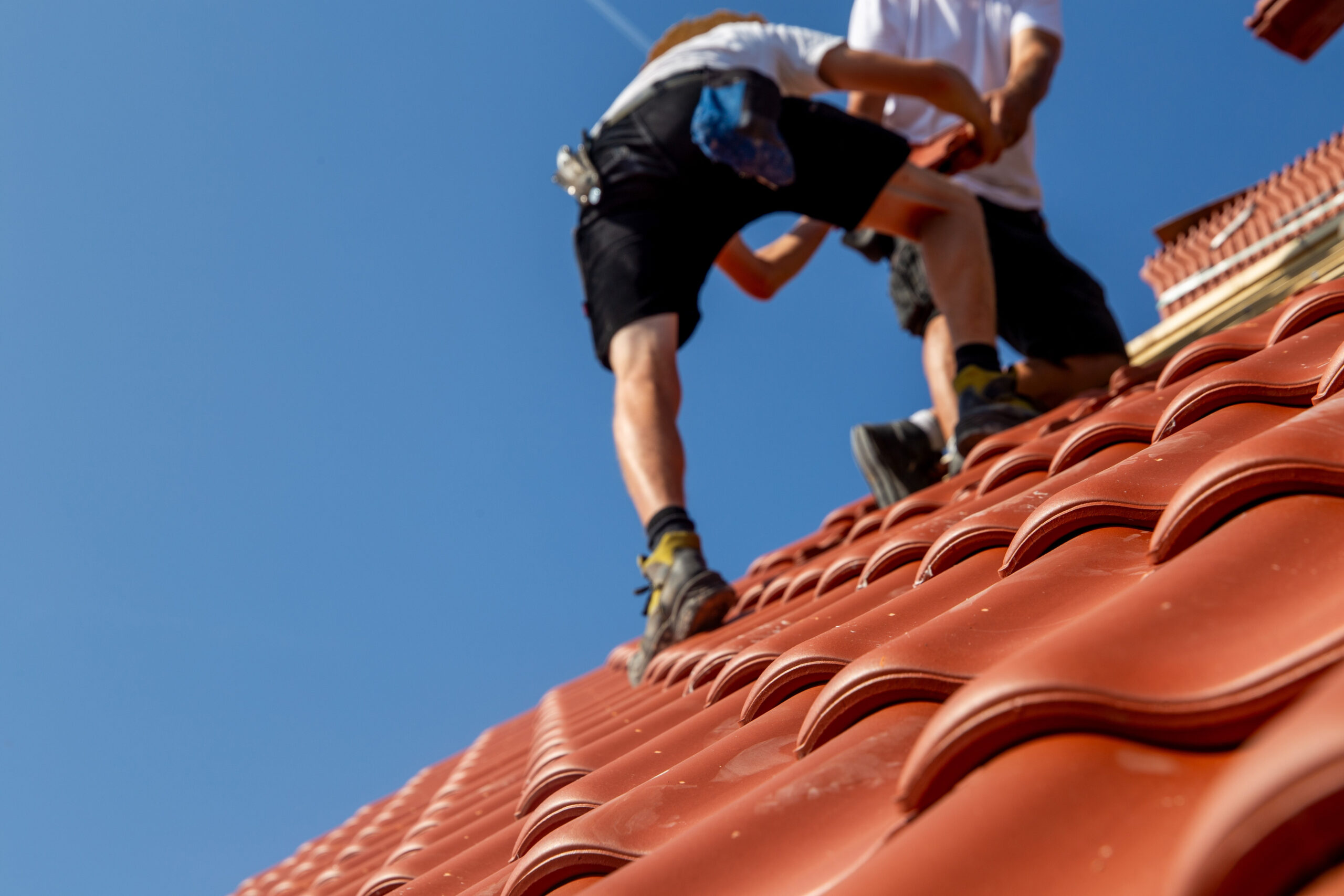 Roofer laying red roof tiles on a pitched roof